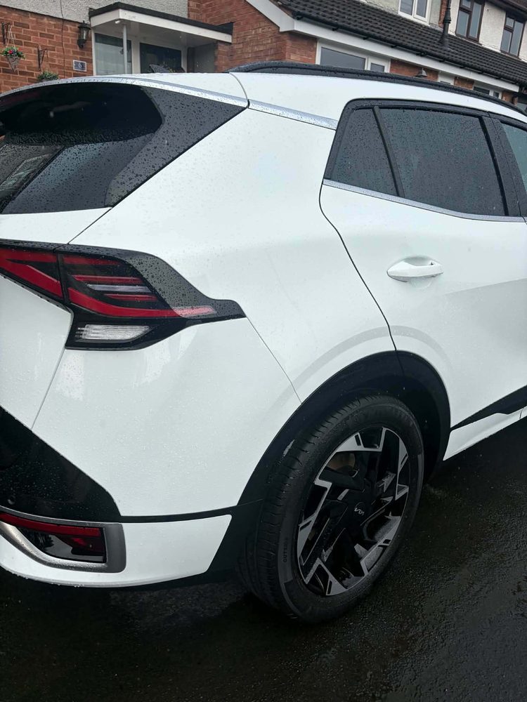 The rear quarter of a white Kia Sportage after a valet, with clean paintwork and wheel