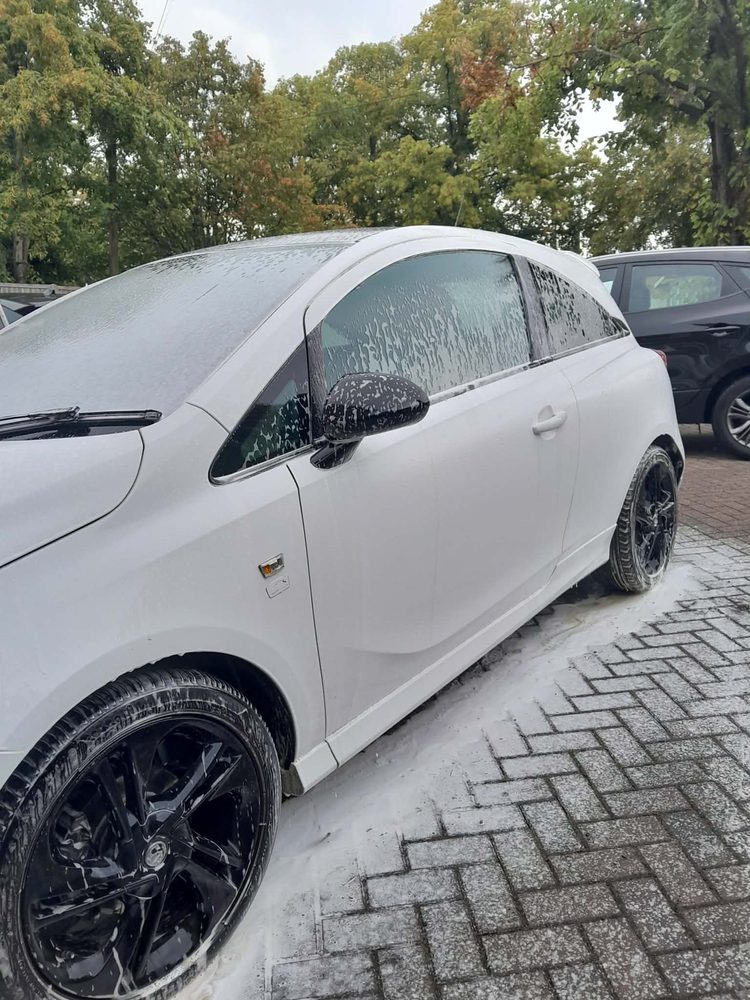The side of a white Vauxhall Corsa after a valet, with black alloy wheels cleaned and dressed