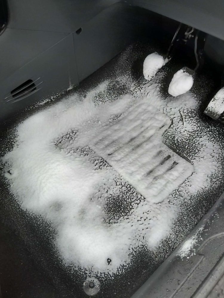 A car mat being deep cleaned with foam lifting the dirt out of the pile
