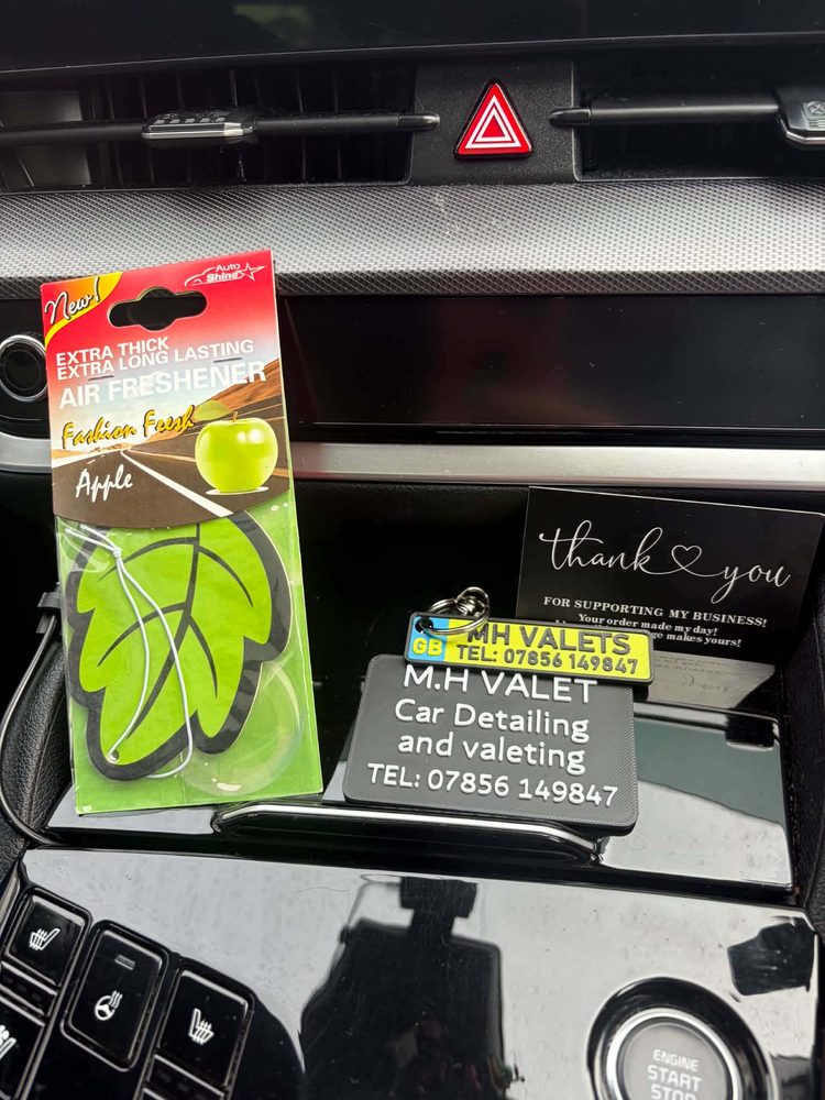 An MH Valets thank you card and an air freshener left on the centre console of a finished car