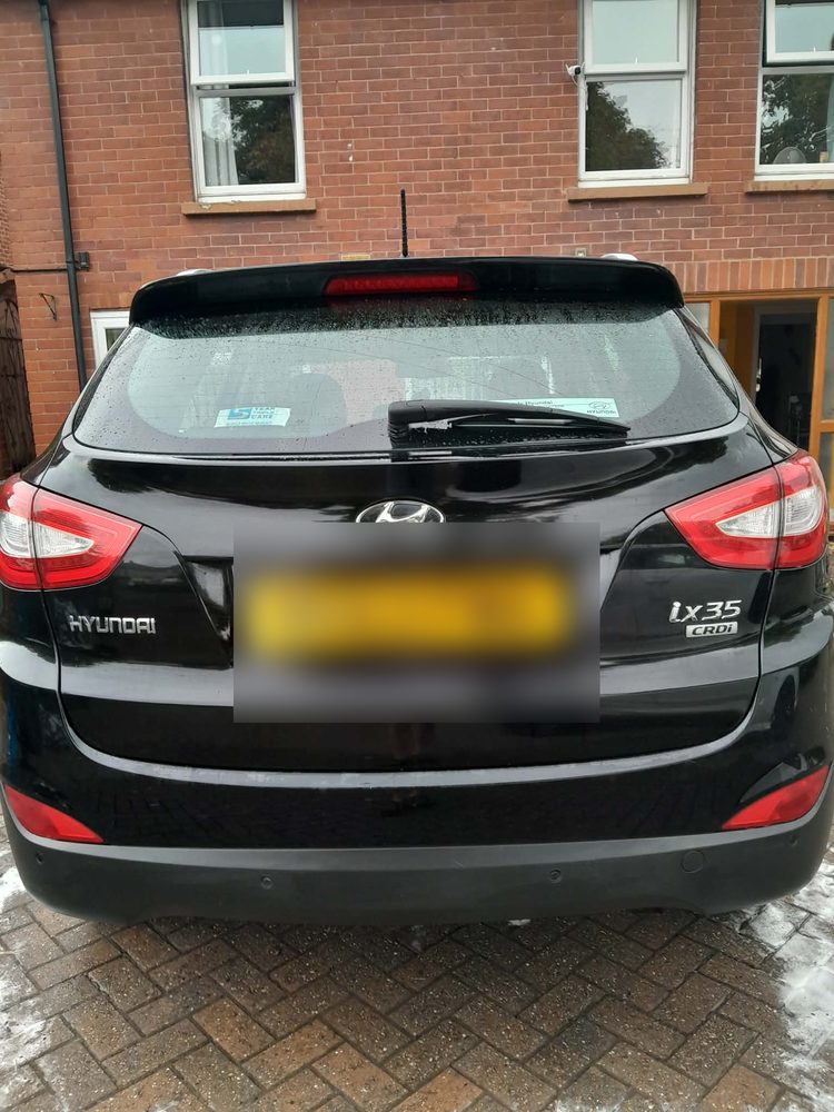 The rear of a black Hyundai ix35 washed and dried on a block paved driveway