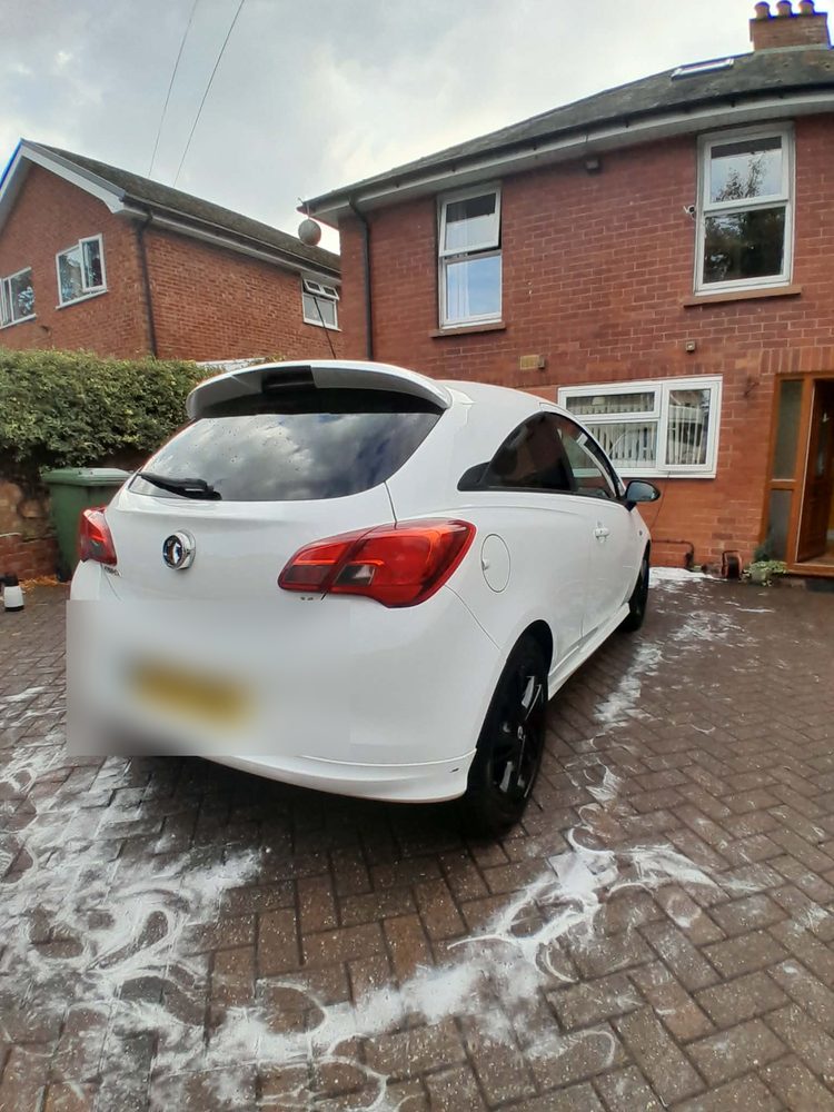 The rear of a white Vauxhall Corsa on a foamed driveway after a full valet
